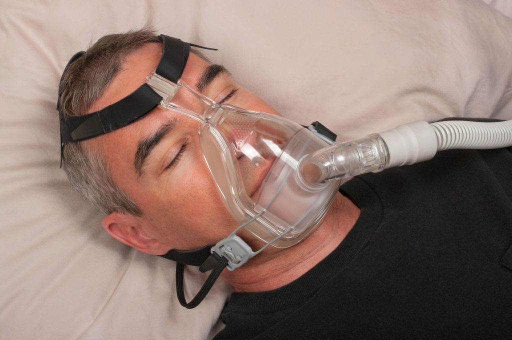 man with Phillips sleep apnea sleeps with apparatus