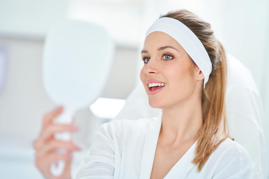 a woman looking in the mirror after getting botox & Xeomin in park falls