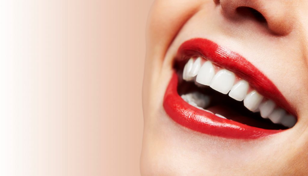 a woman wearing red lipstick smiling after getting phillips teeth whitening