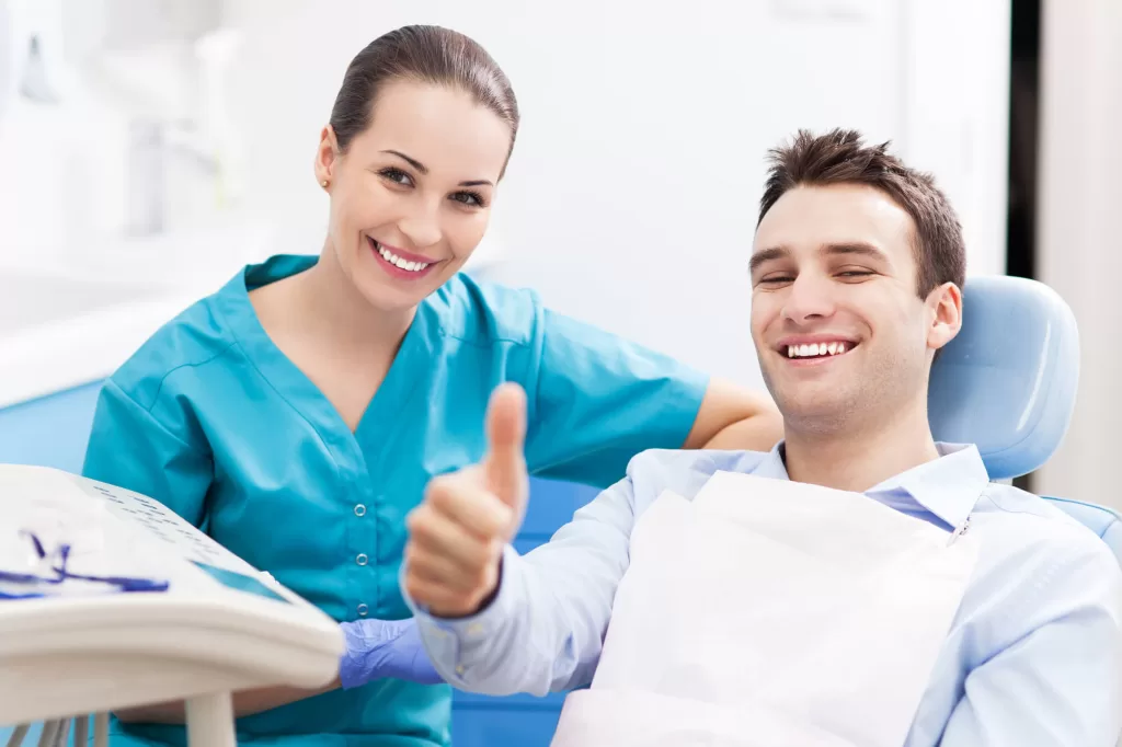 Dental patient giving thumbs up next to dentist before administering sedation dentistry in Medford